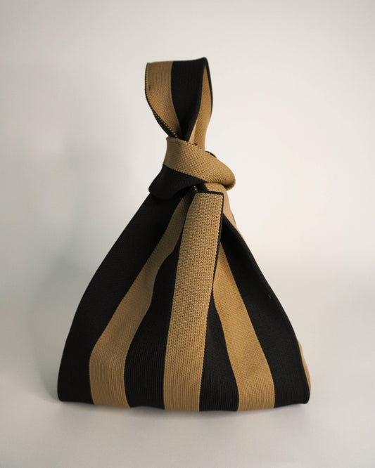 Black and beige striped bag with a knot on a white background