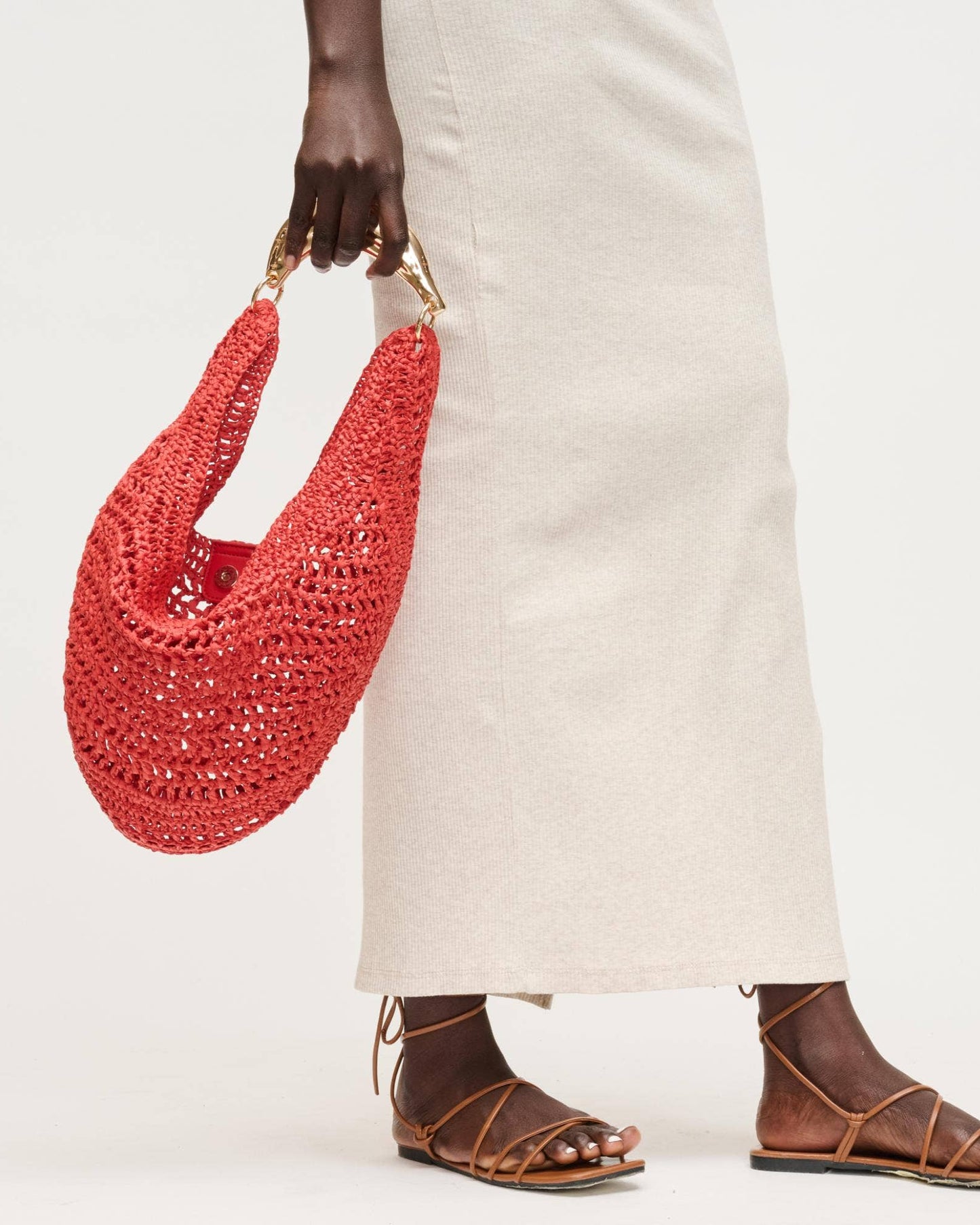Person holding a red woven handbag with a plain background