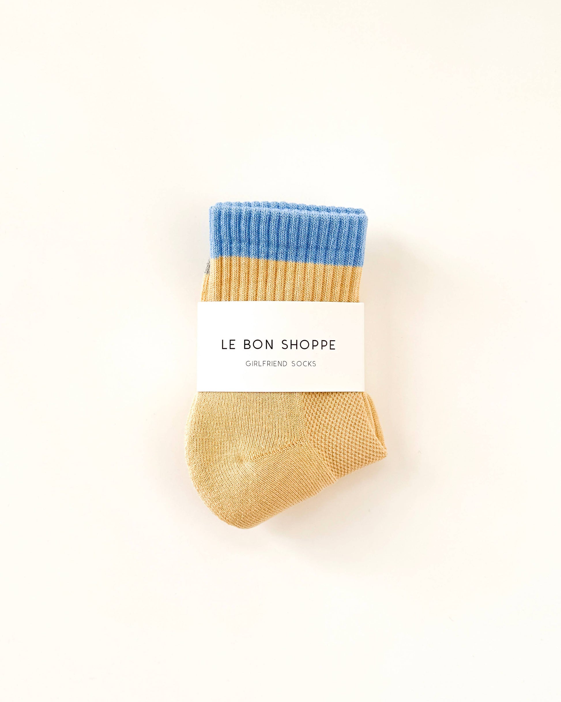 Pair of blue and beige socks with 'Le Bon Shoppe' label on a white background