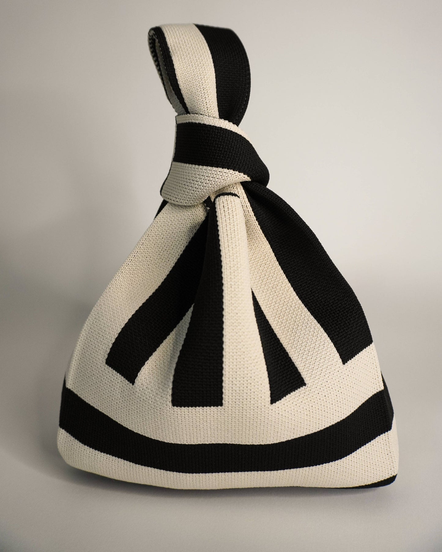 Black and white striped knitted bag on a gray background