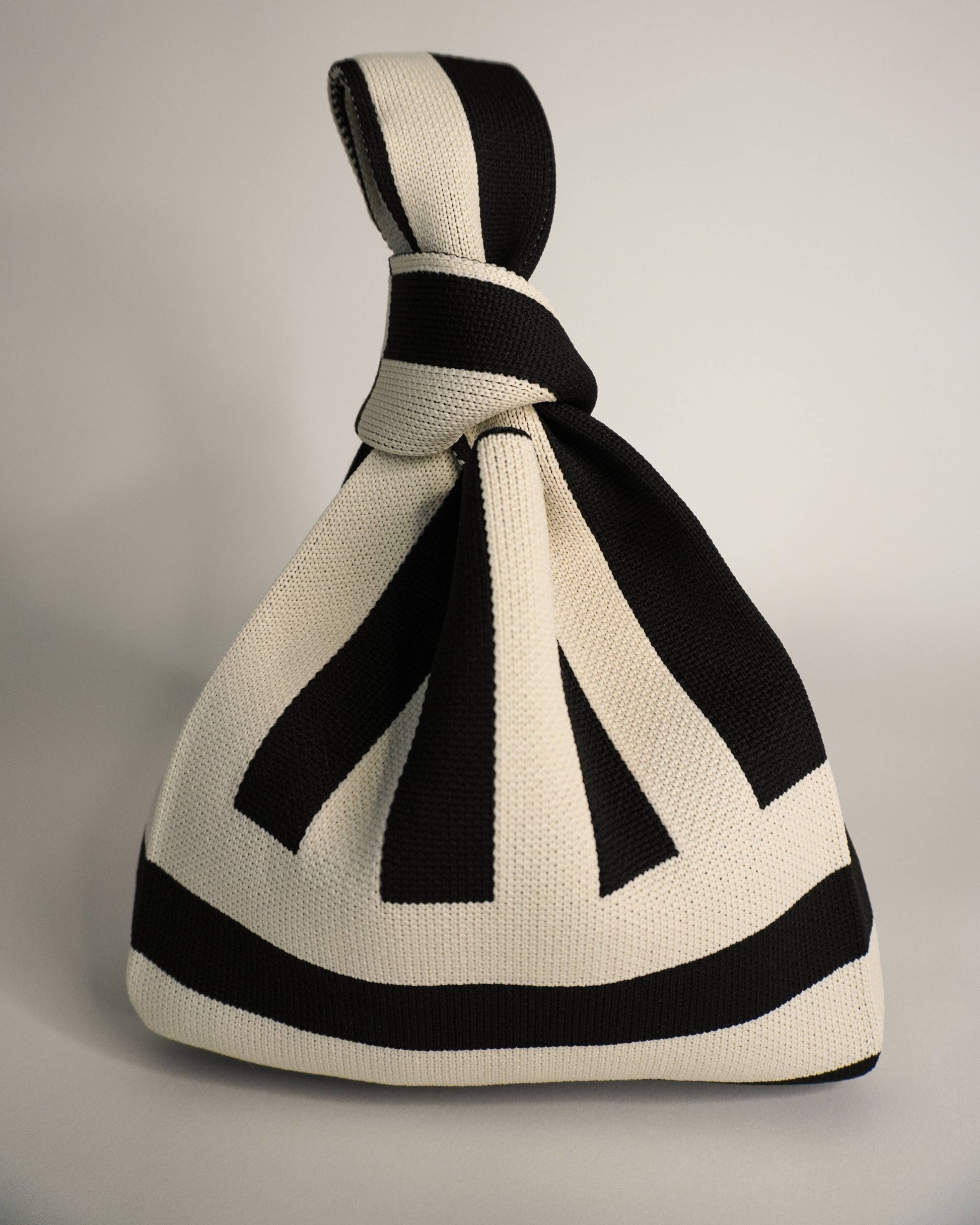 Black and white striped knitted bag on a gray background