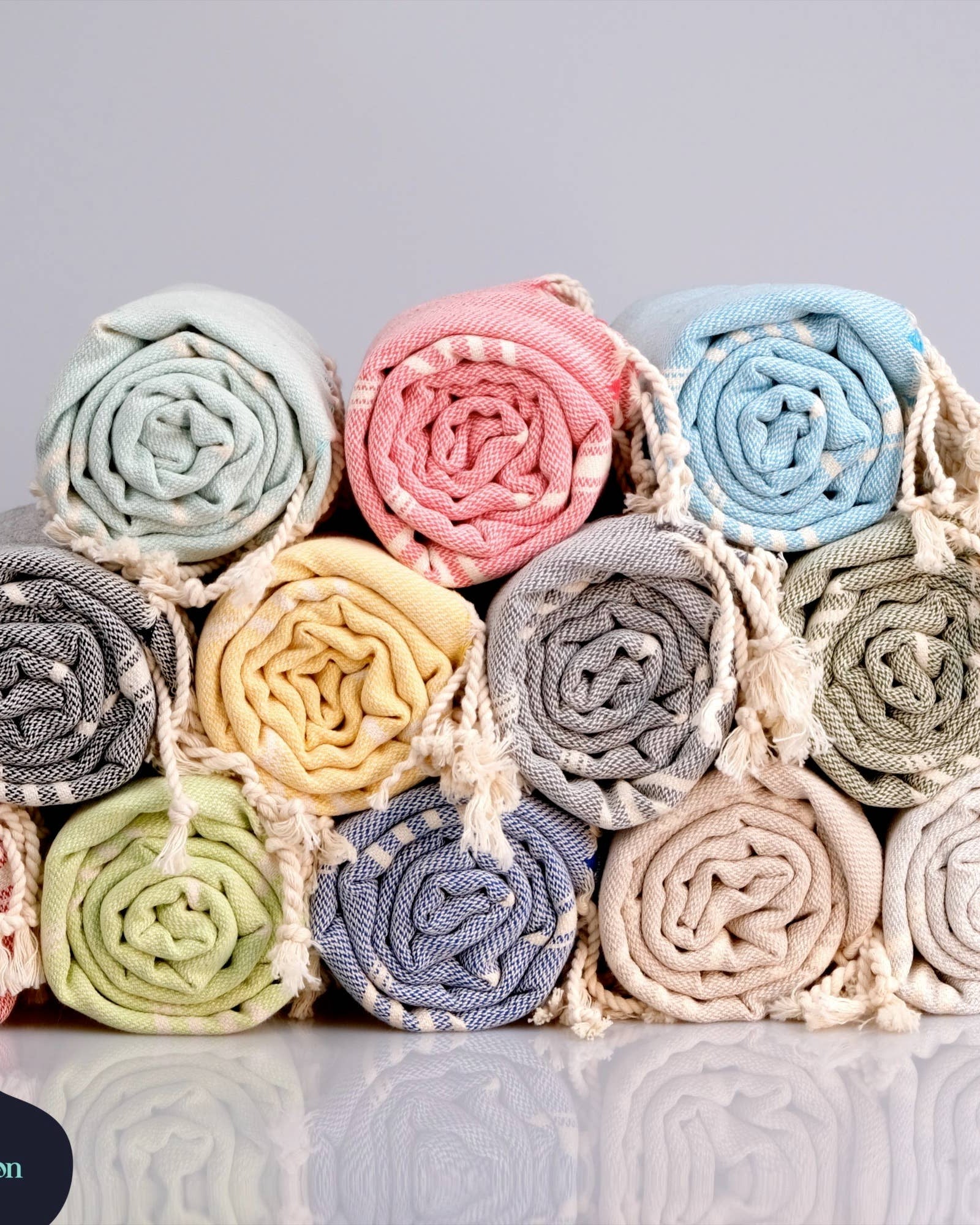 Stack of rolled-up towels in pastel colors with a visible brand logo.