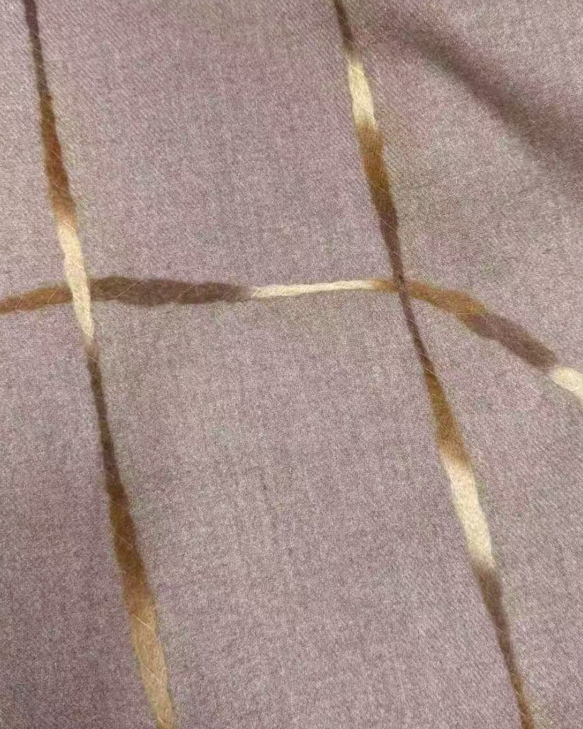 A close-up of a textured fabric in a muted taupe-brown color with a gold grid pattern.