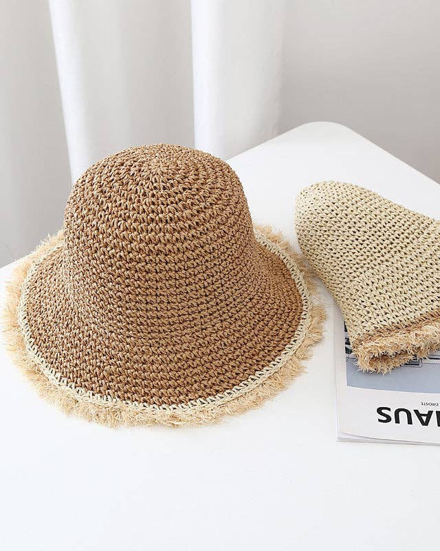 Two straw hats on a white surface with a magazine underneath.