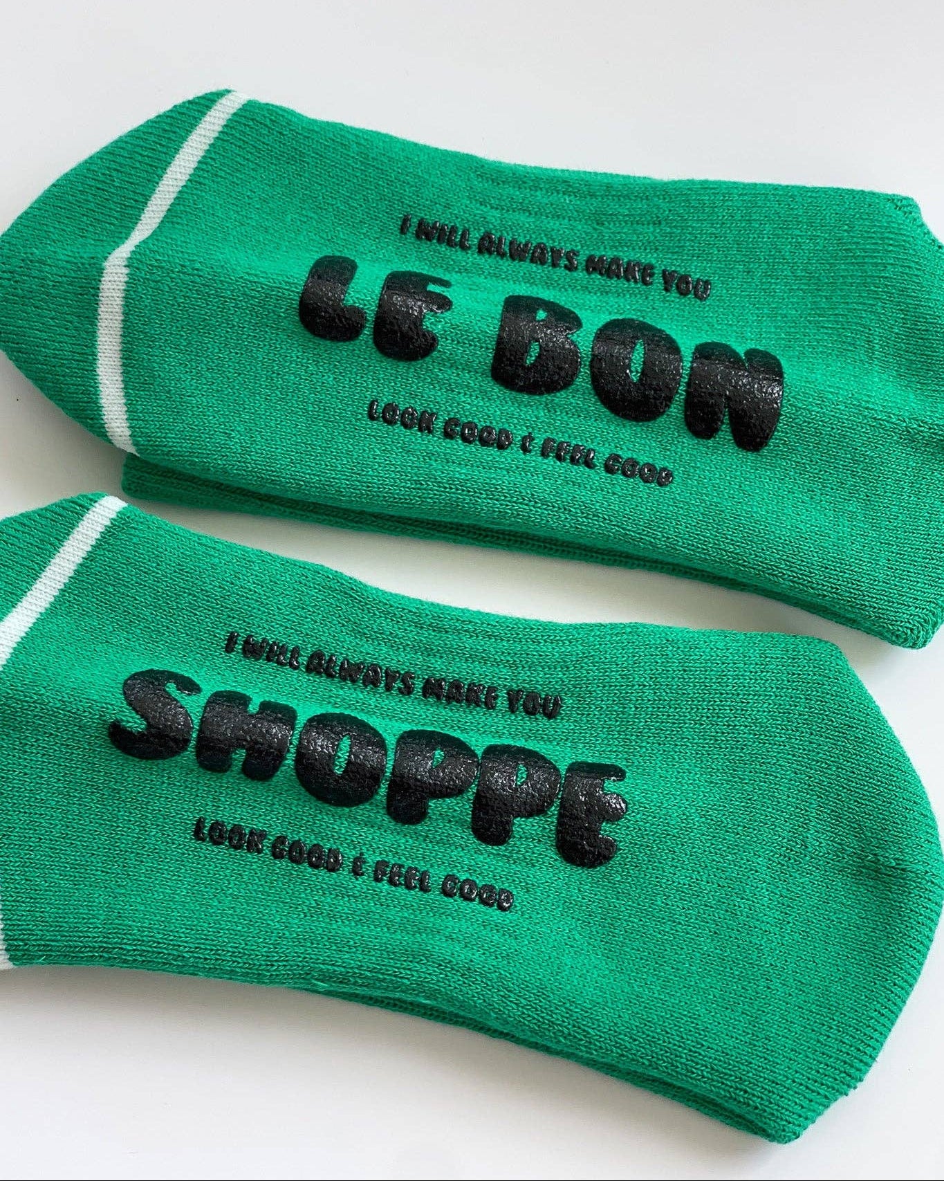 Two green socks with black text on a white background