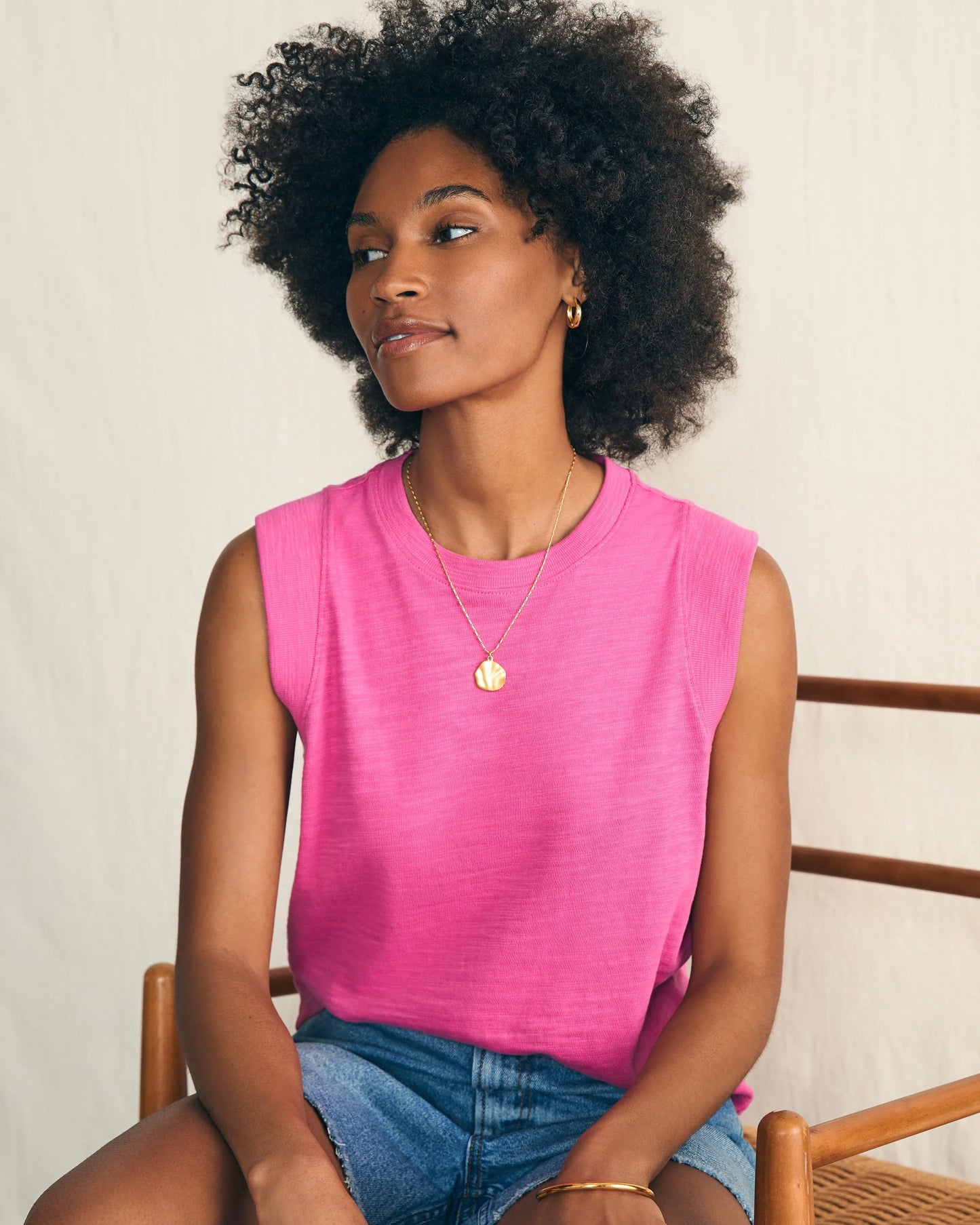 Model wearing Faherty Sunwashed Sub Muscle Tank in Cone flower pink wearing jean shorts on a white background