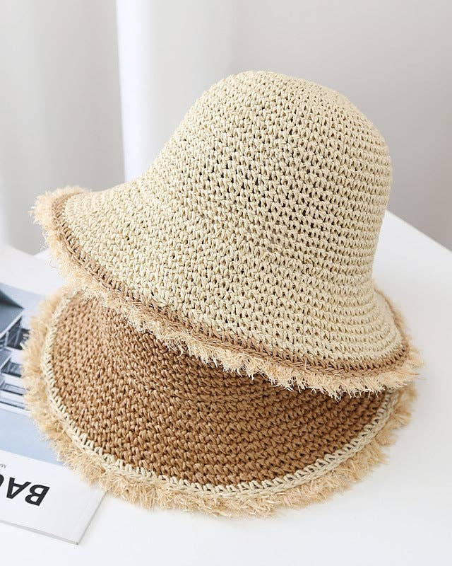 Beige straw hat with fringe on a white surface