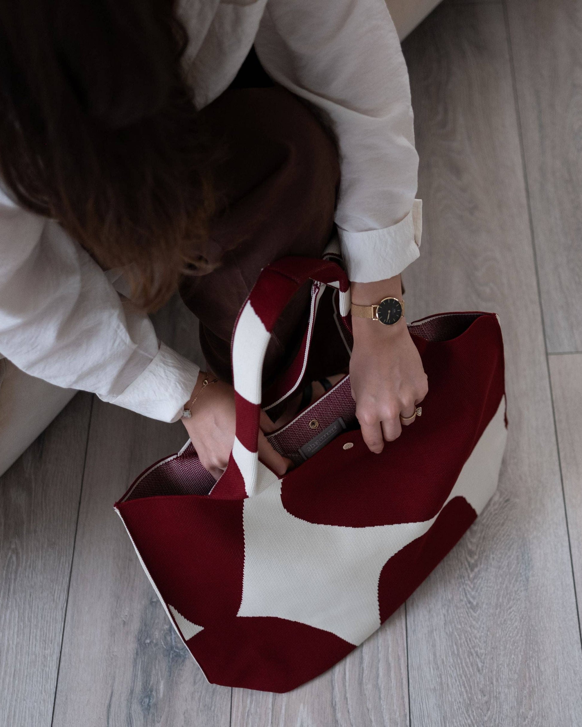 Person interacting with a red and white patterned bag on a wooden floor