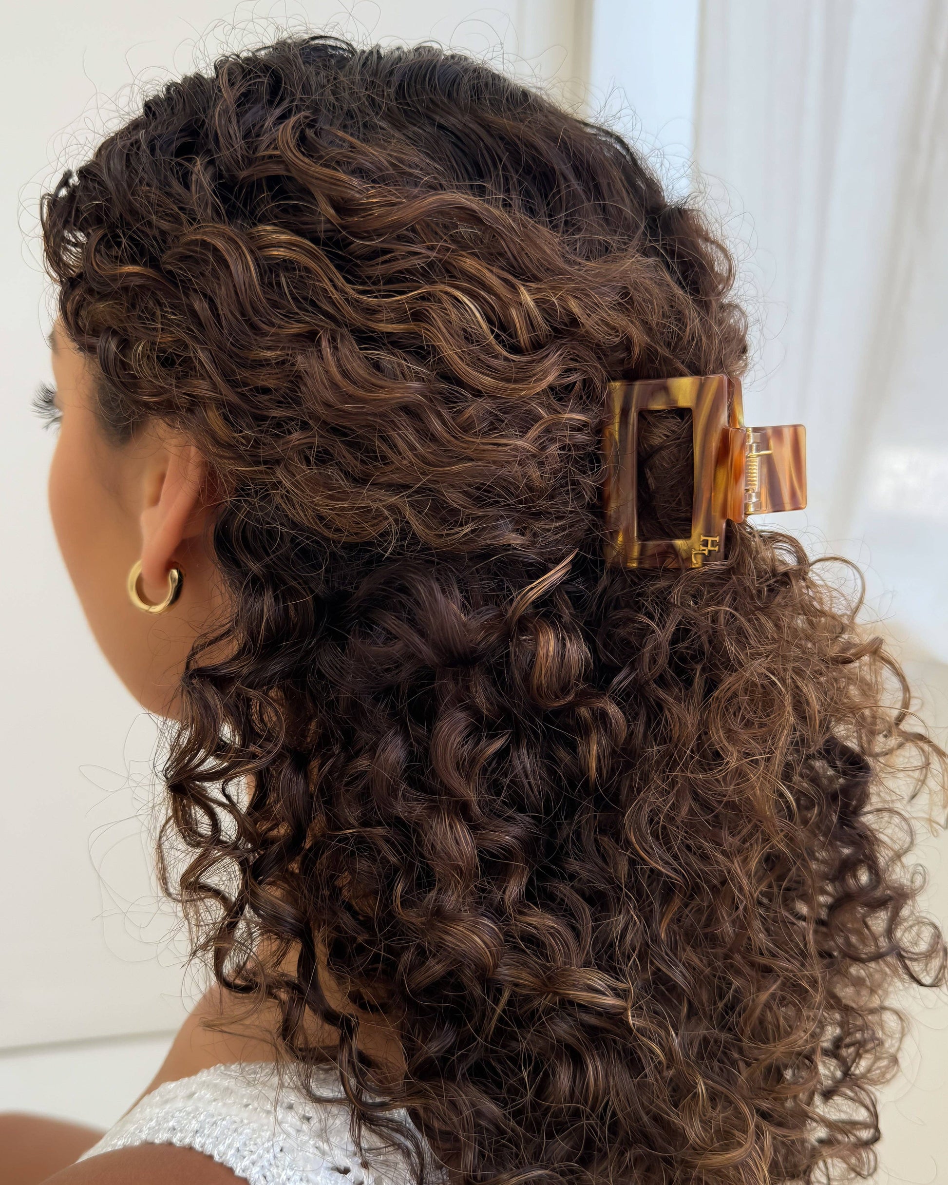 Woman with curly hair wearing the HoneyLux Ecofriendly Acetate Midi Clip in the color Hazel Honey against a neutral background