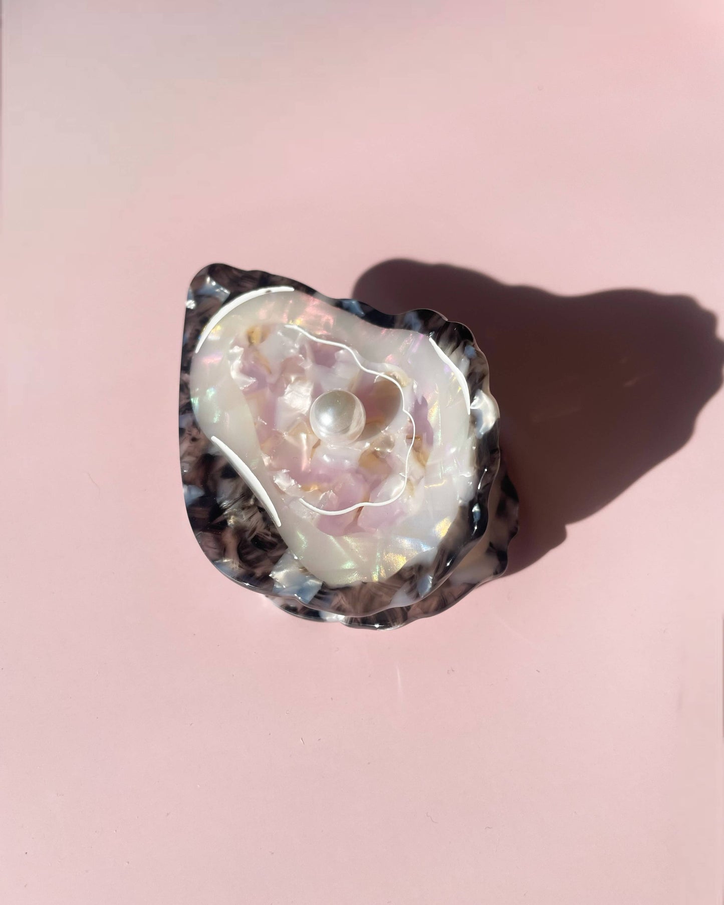 Front view of the Line&Co oyster claw clip laying on a pink background