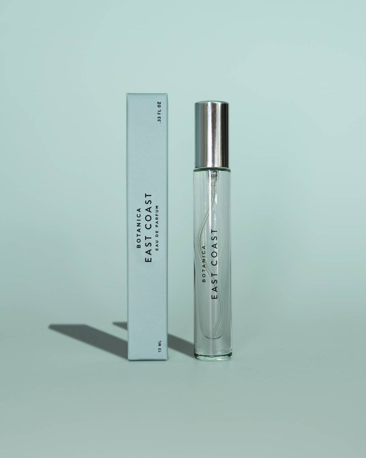 Perfume bottle and packaging with 'Botanica East Coast' branding on a light green background