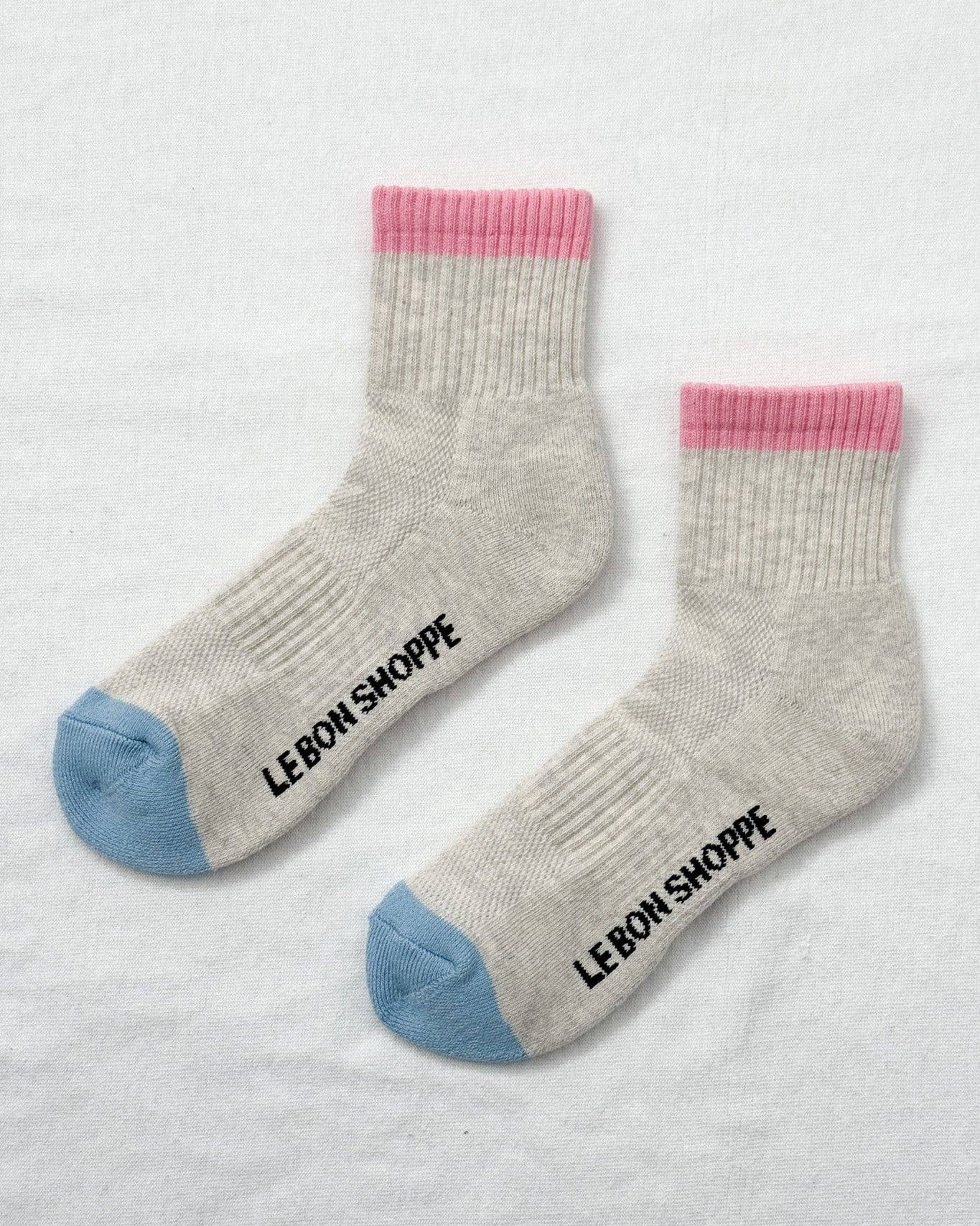 Gray socks with pink and blue accents and 'Le Bon Shoppe' branding on a light gray background