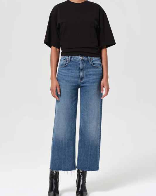 Person wearing a black top and blue jeans on a white background