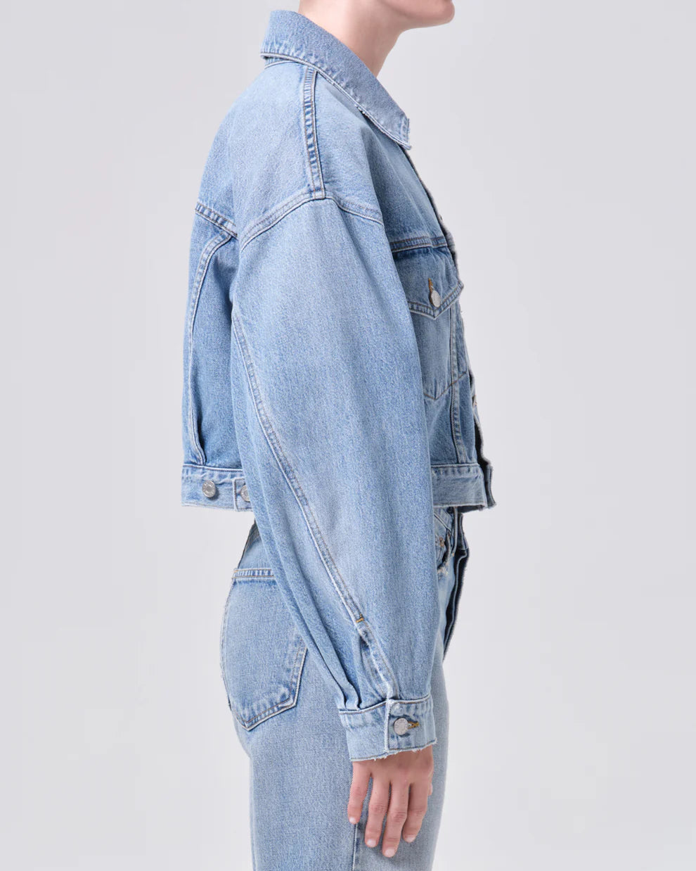 Light blue denim jacket worn by a person on a light gray background