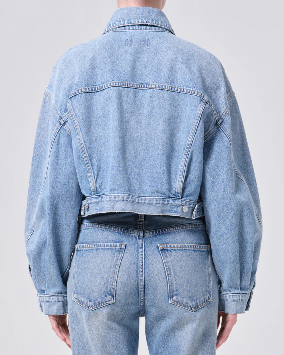 Light blue denim jacket and jeans on a plain background