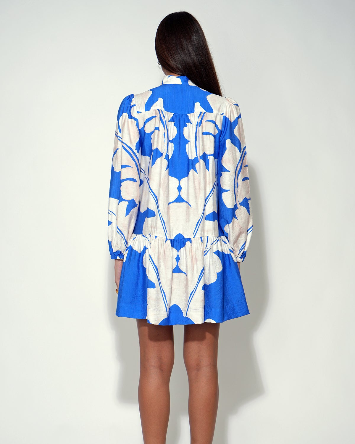 Woman wearing a blue and white floral dress against a white background