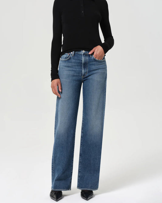Person wearing a black long-sleeve shirt and blue jeans on a white background