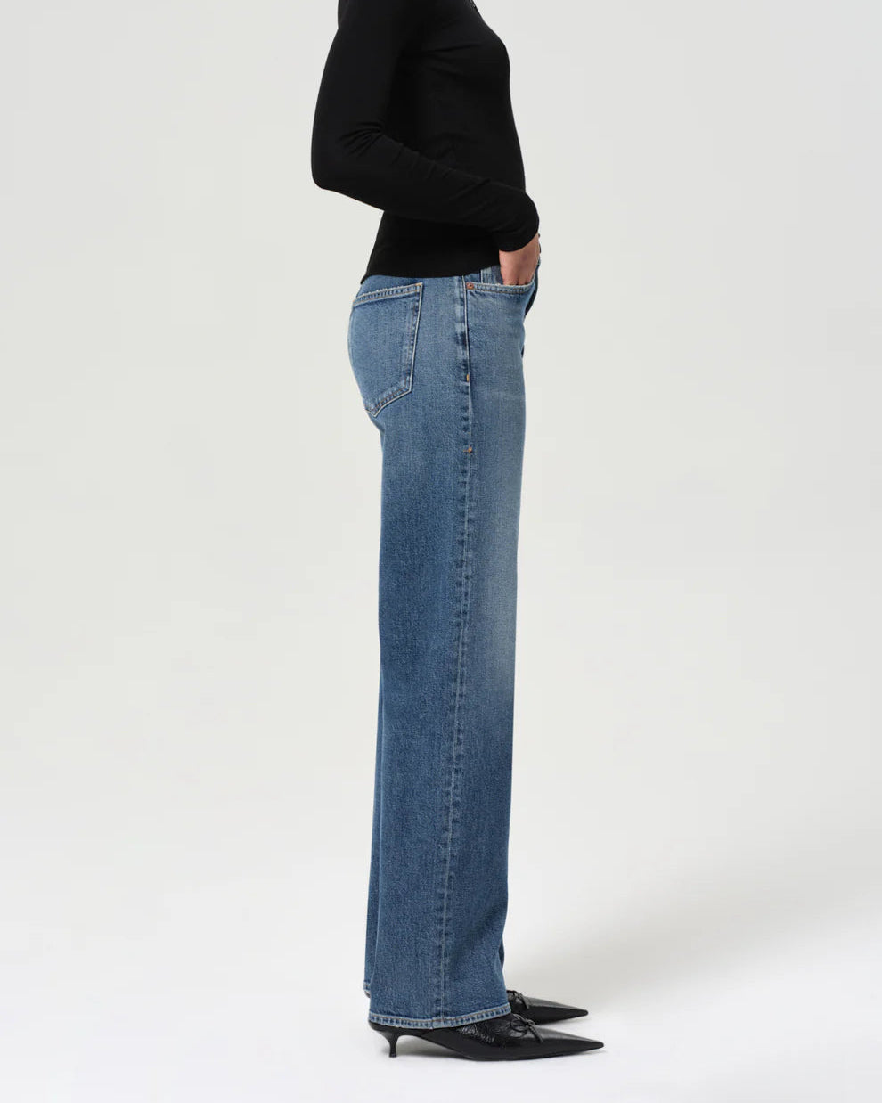 Person wearing a black sweater and blue jeans on a white background