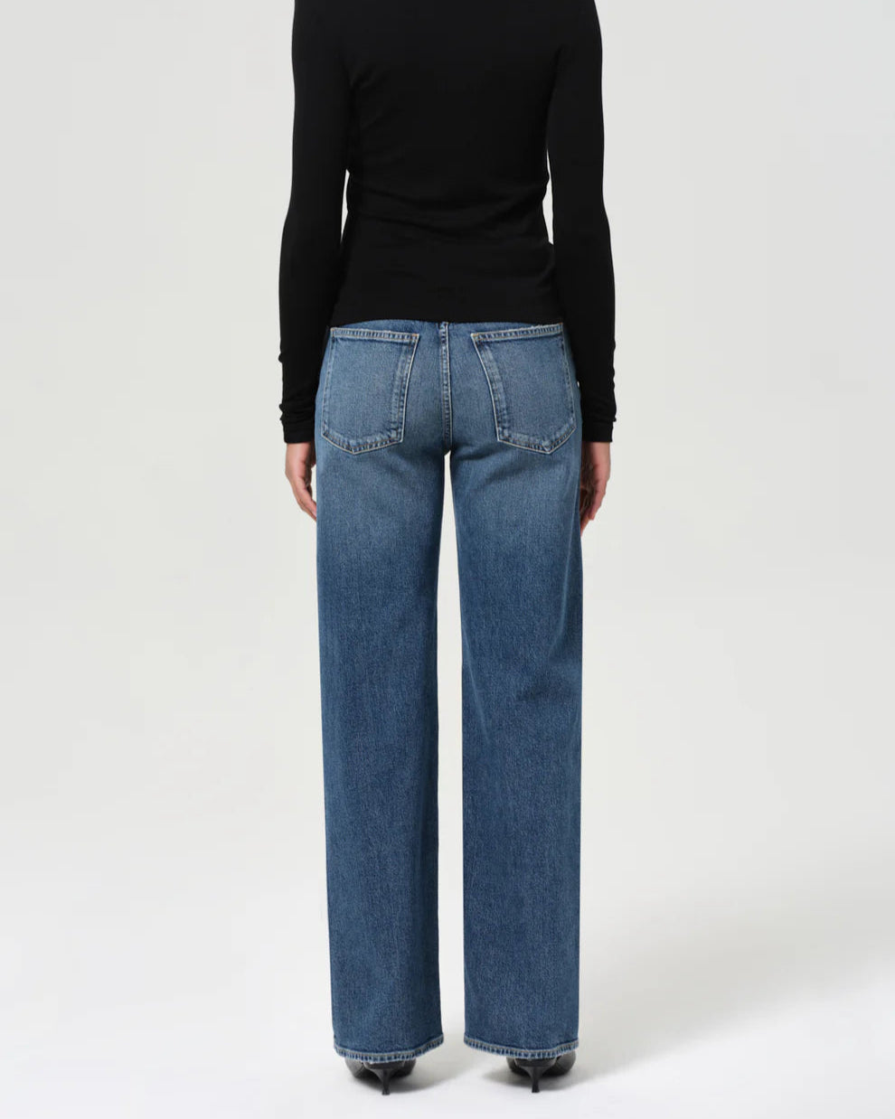 Person wearing a black turtleneck and blue jeans on a white background