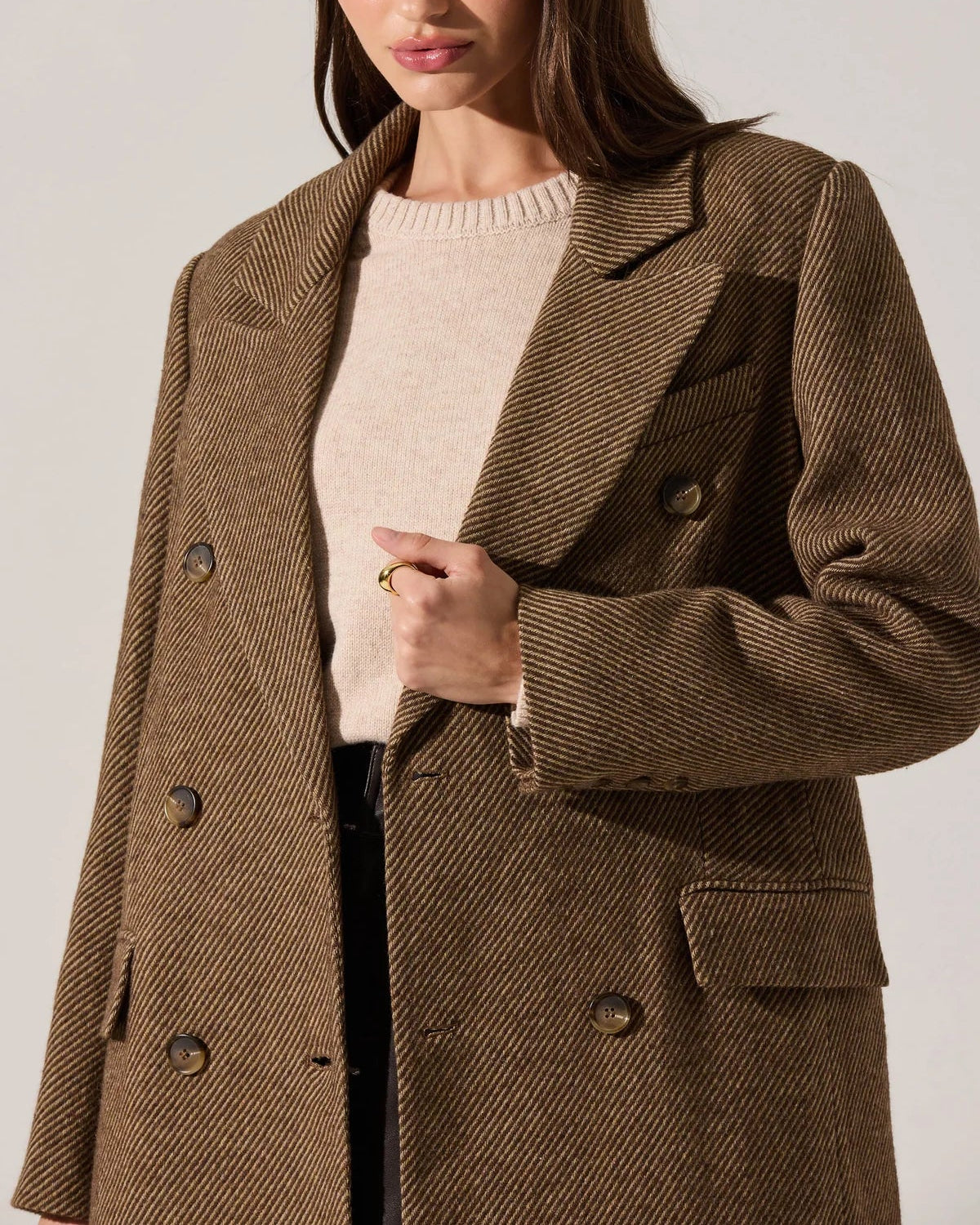 Woman wearing a brown coat against a plain background