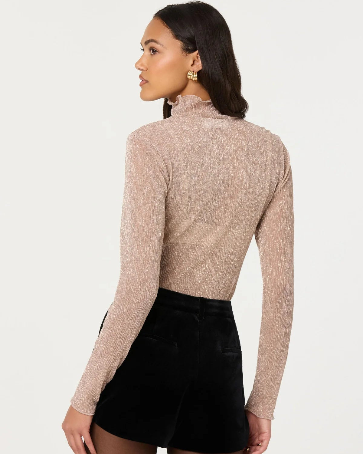 Woman wearing a beige long-sleeve top and black skirt on a white background