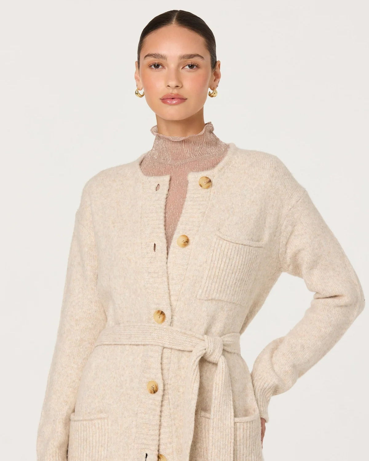 Woman wearing a beige cardigan with buttons on a white background