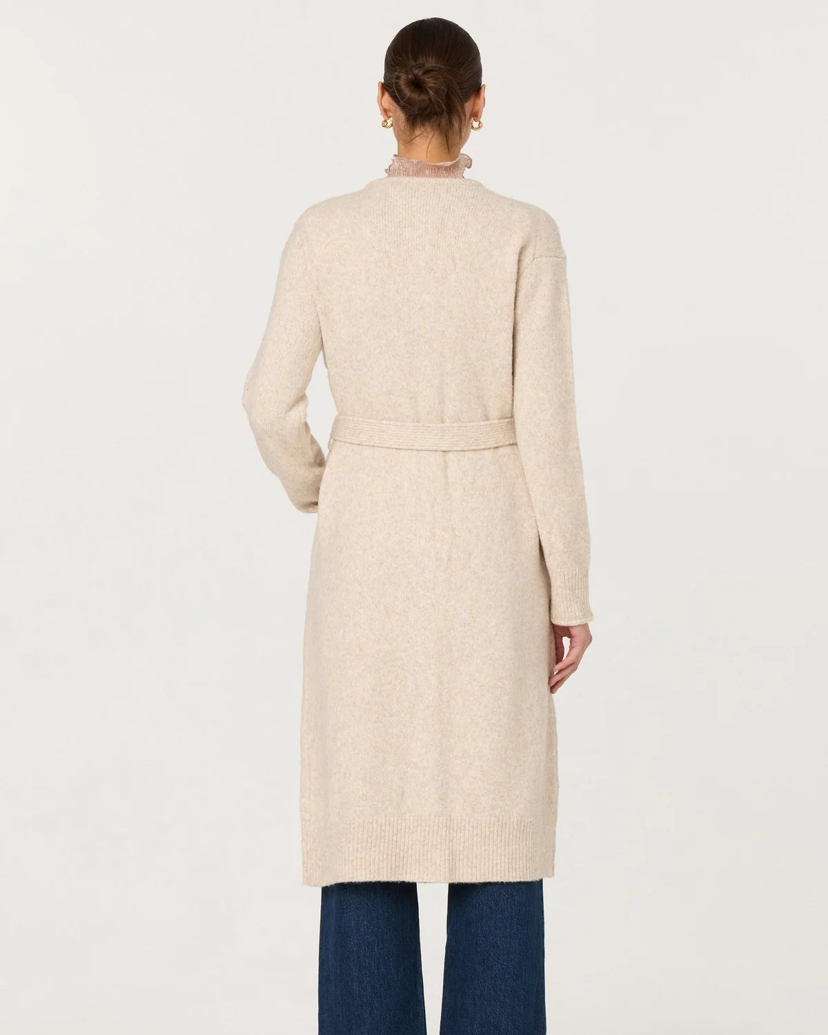 Person wearing a beige coat and blue pants on a white background