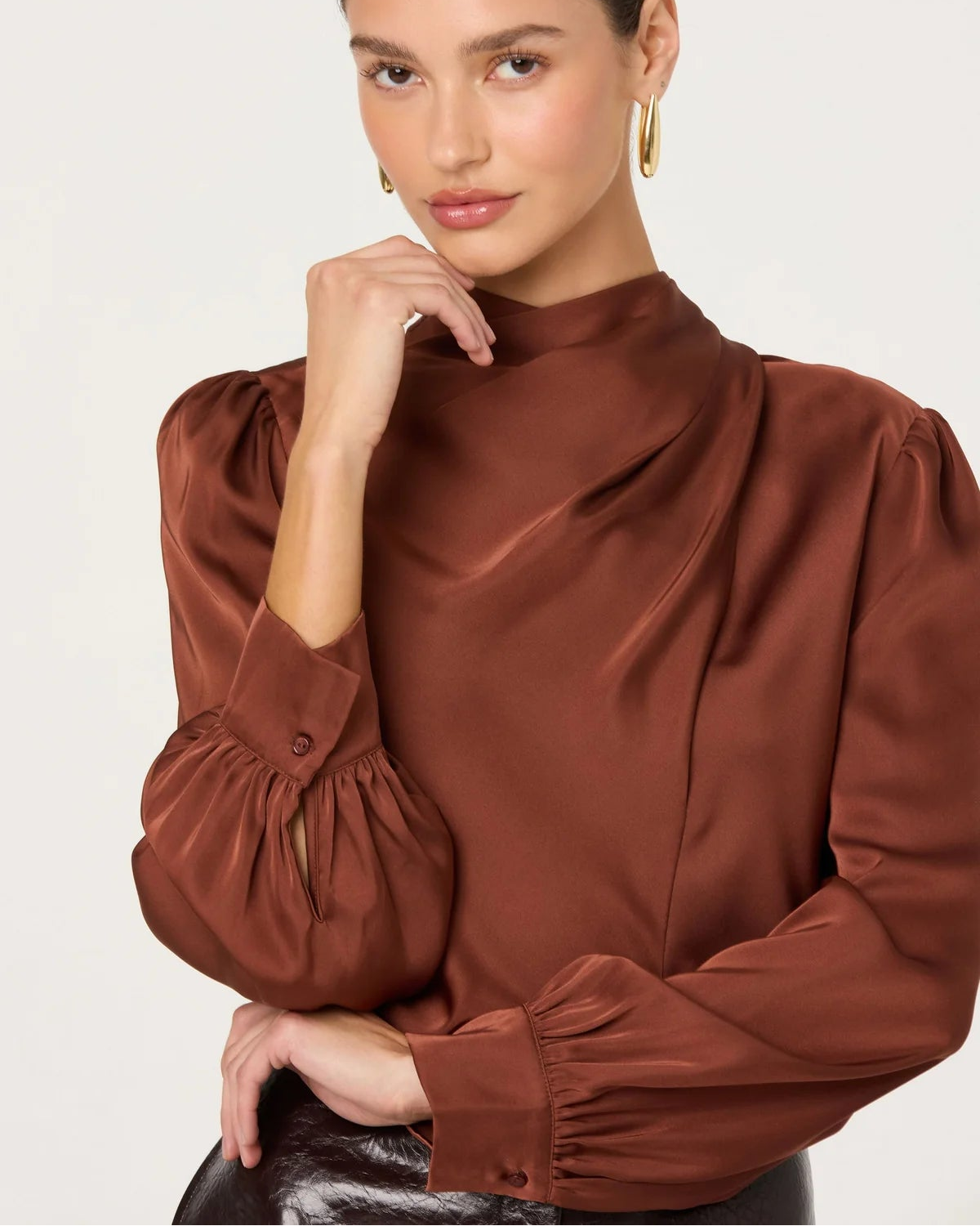 Woman wearing a brown blouse with puffed sleeves against a white background
