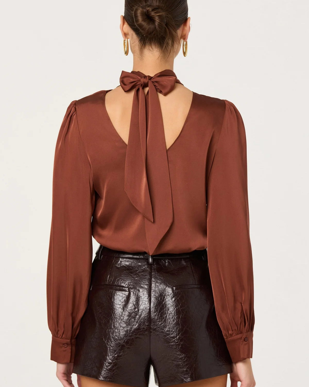 Brown blouse with a bow detail on the back worn by a person, against a white background