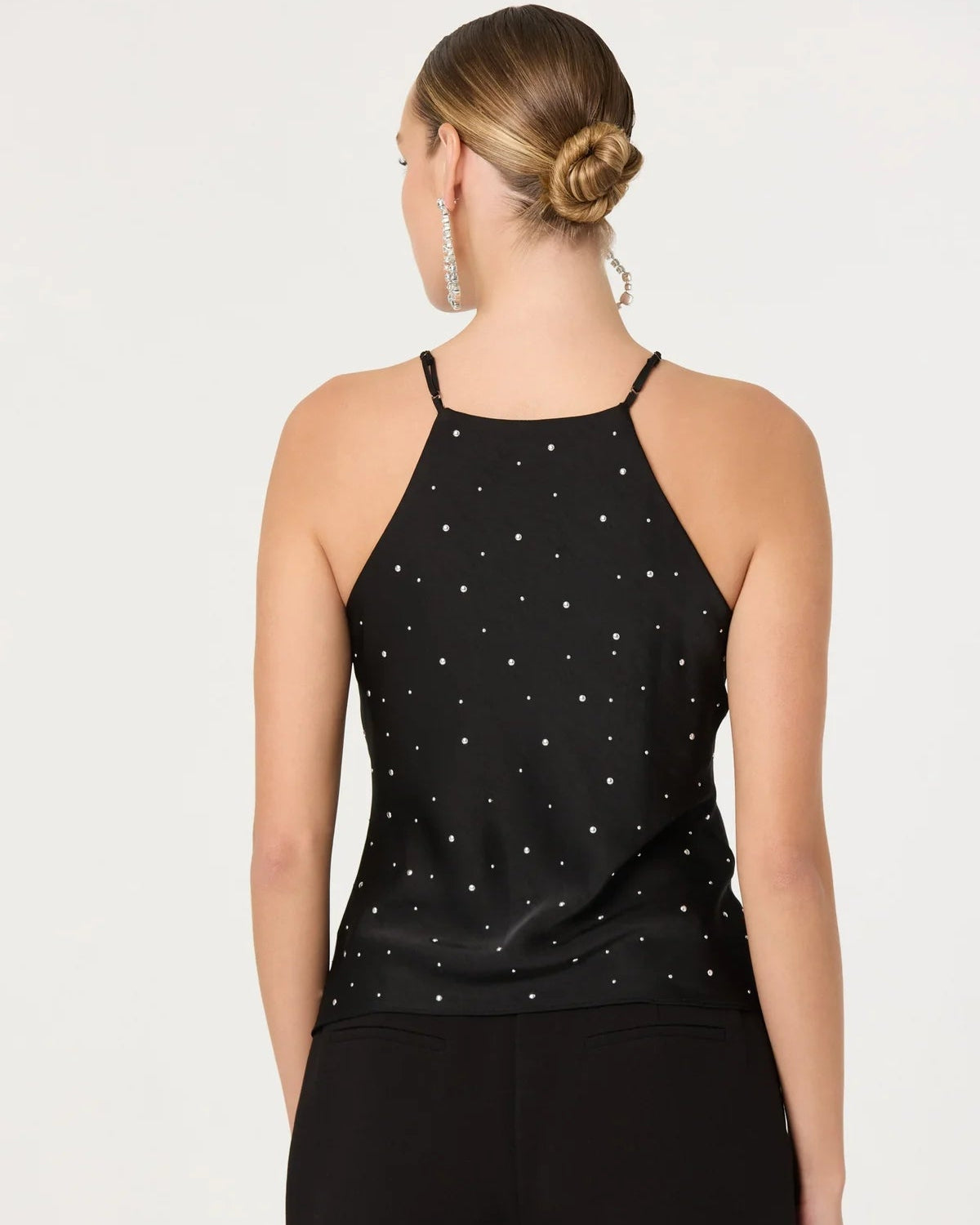 Woman wearing a black tank top with star patterns and black shorts on a white background