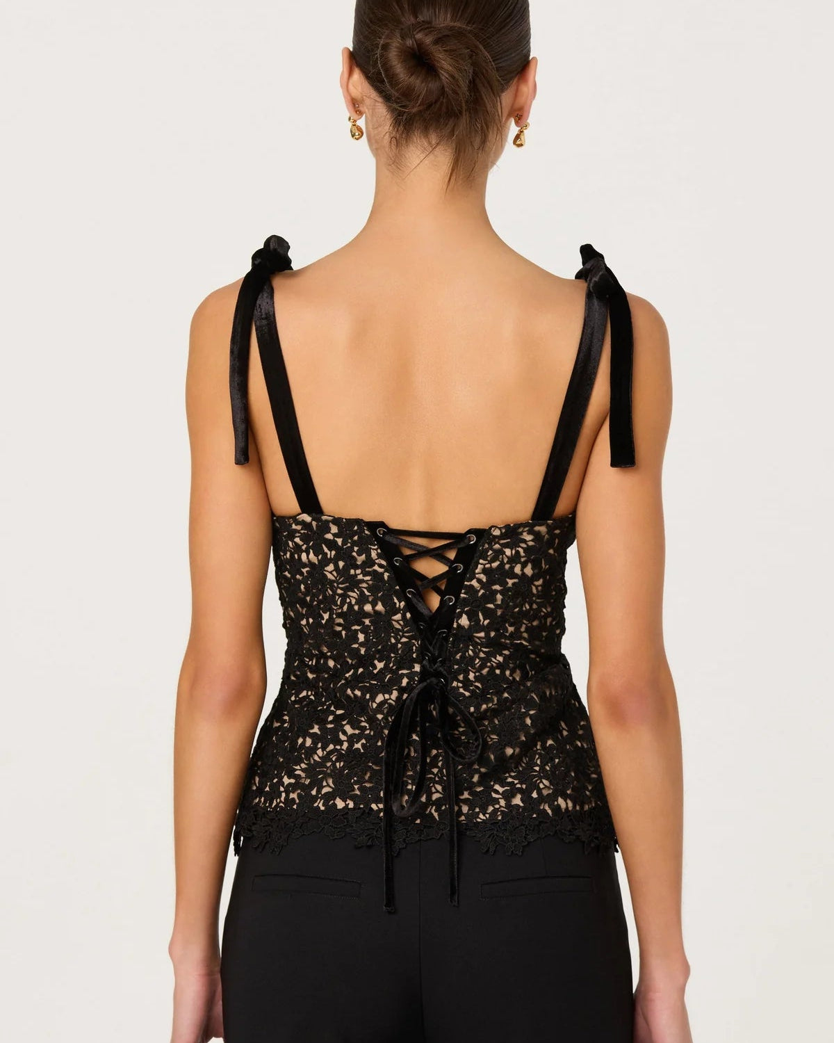 Black lace-up top worn by a model on a white background