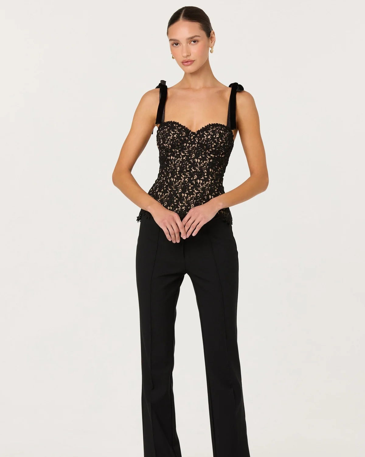 Woman wearing a black outfit with a strapless top and flared pants on a white background