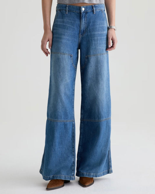 Wide-leg blue jeans worn by a person on a white background