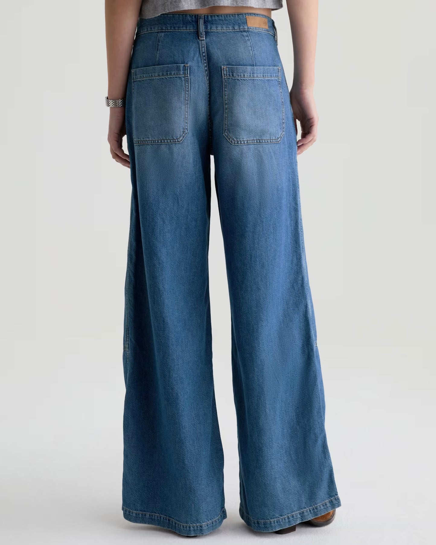 Blue wide-leg jeans worn by a person on a light gray background