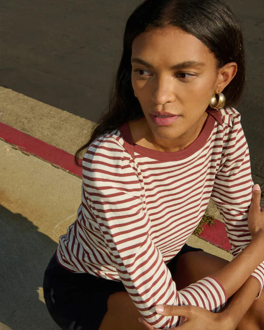 Woman wearing a red and white striped shirt sitting on a step.