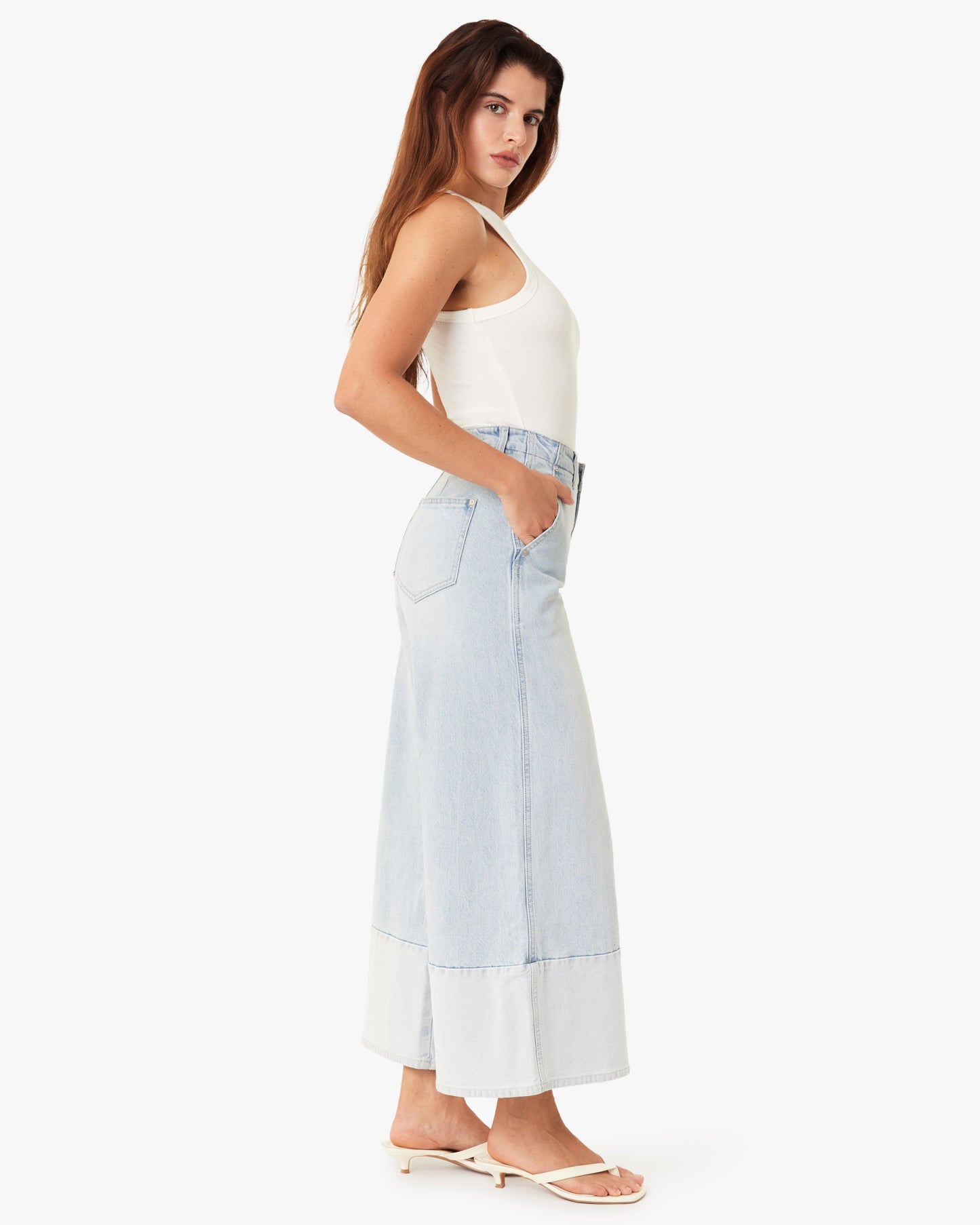Woman wearing a white top and light blue denim skirt on a white background