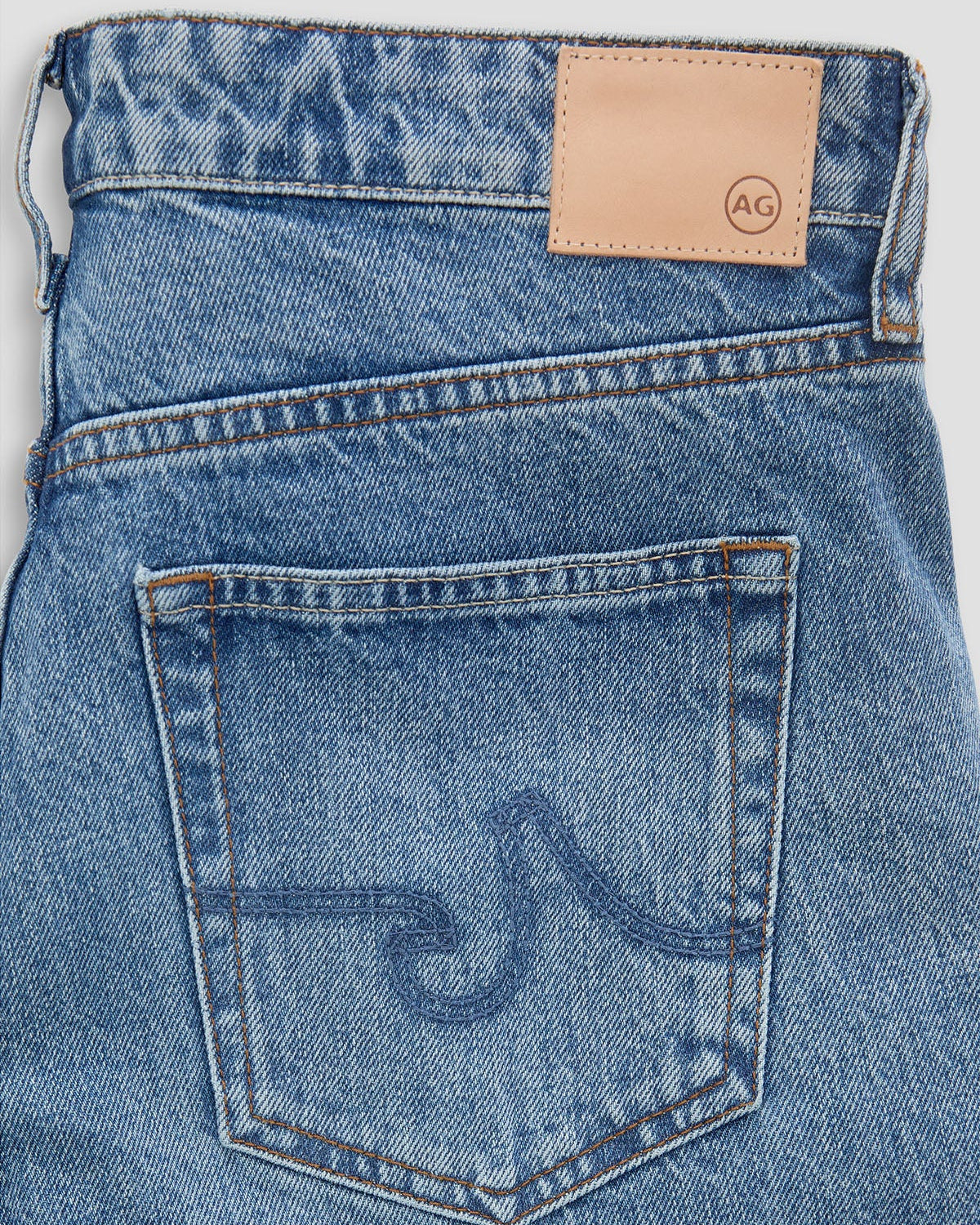 Close-up of blue denim jeans with a brand logo on the back pocket.