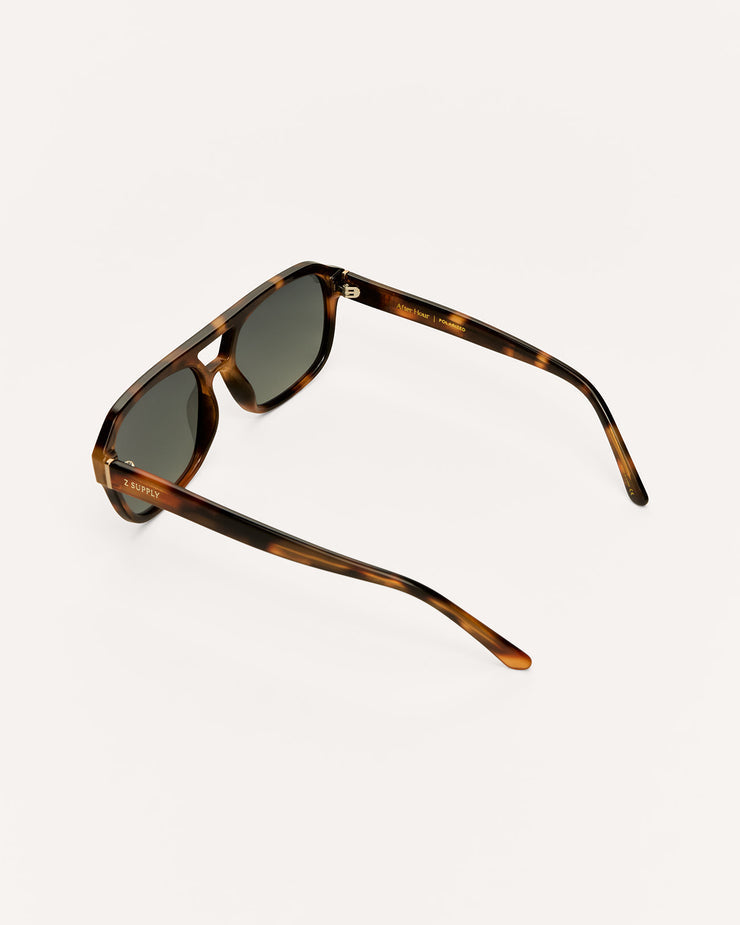 Sunglasses with tortoiseshell frame and dark lenses on a light gray background