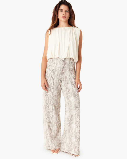 Woman wearing a white sleeveless top and patterned pants on a white background