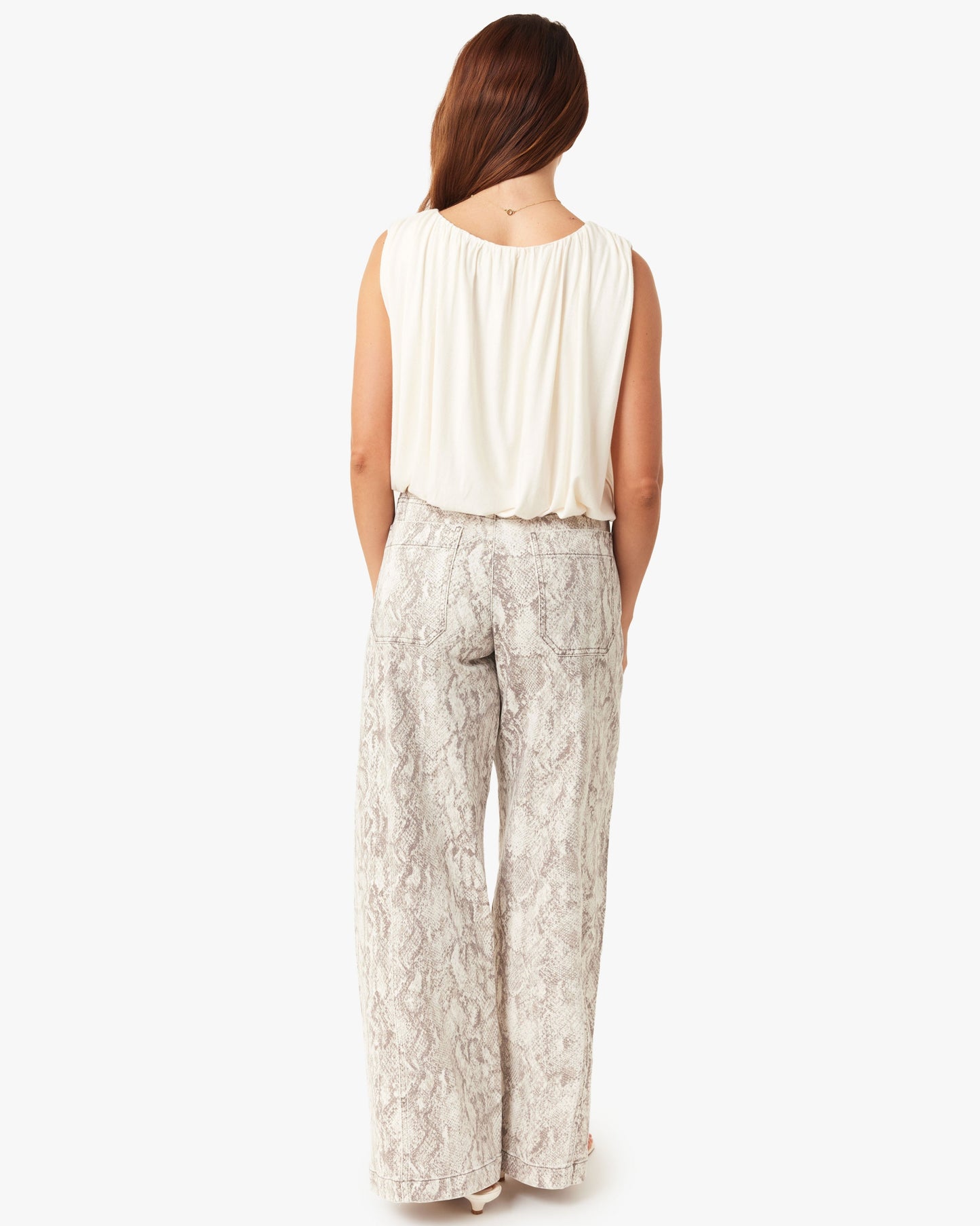 Woman wearing a sleeveless top and patterned pants on a white background