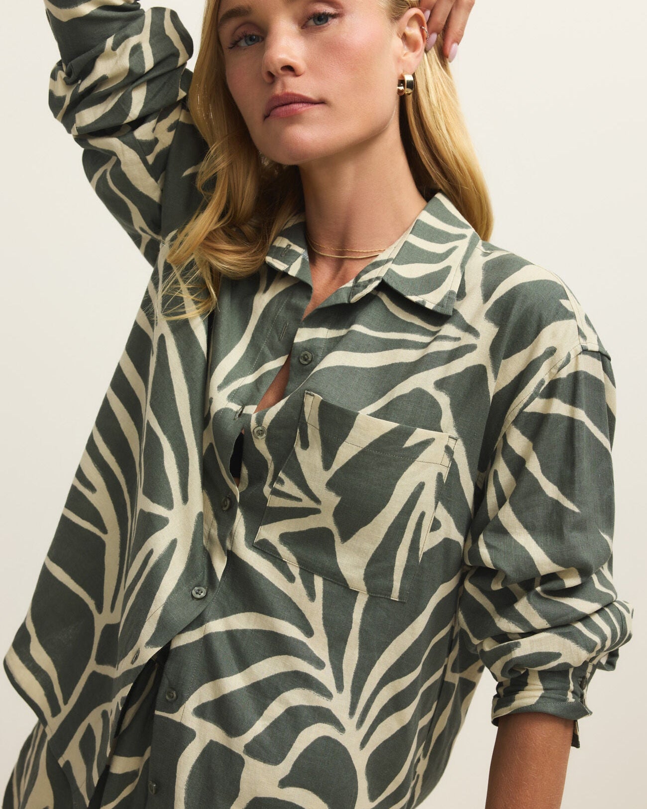 Woman wearing a green and beige patterned shirt against a plain background