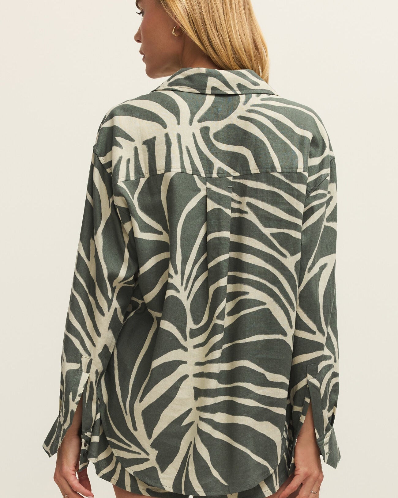 Woman wearing a green and beige patterned shirt against a plain background