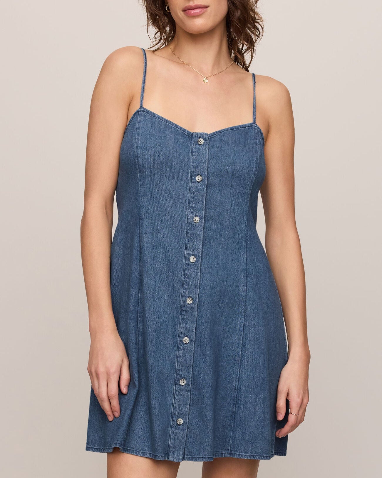 Woman wearing a blue denim dress against a plain background