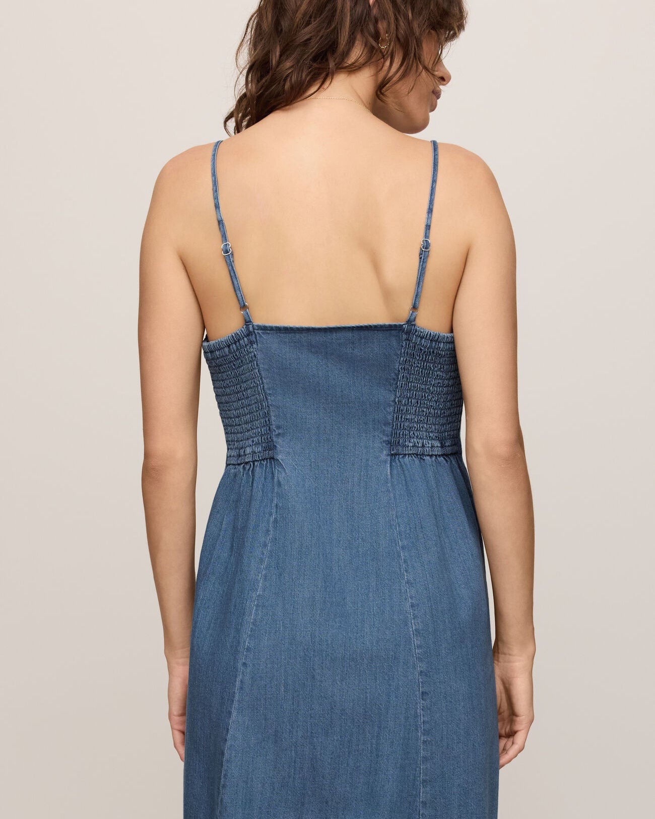 Woman wearing a blue denim dress against a plain background