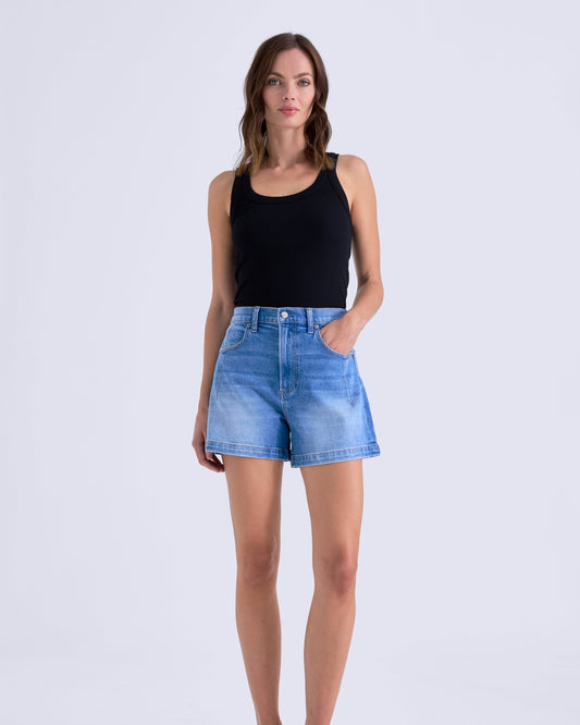 Woman wearing a black tank top and blue denim shorts on a white background