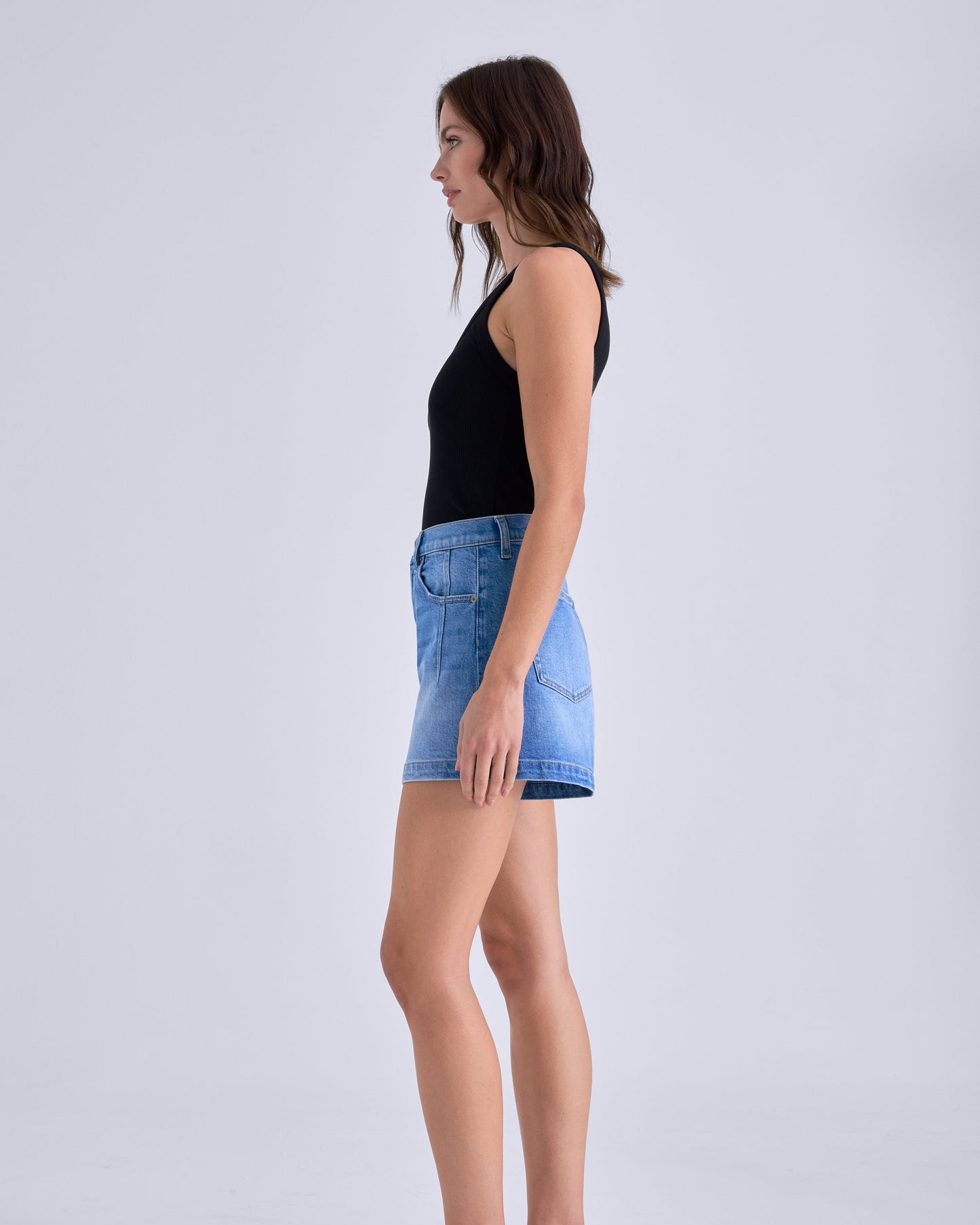 Woman wearing a black top and blue denim shorts on a white background