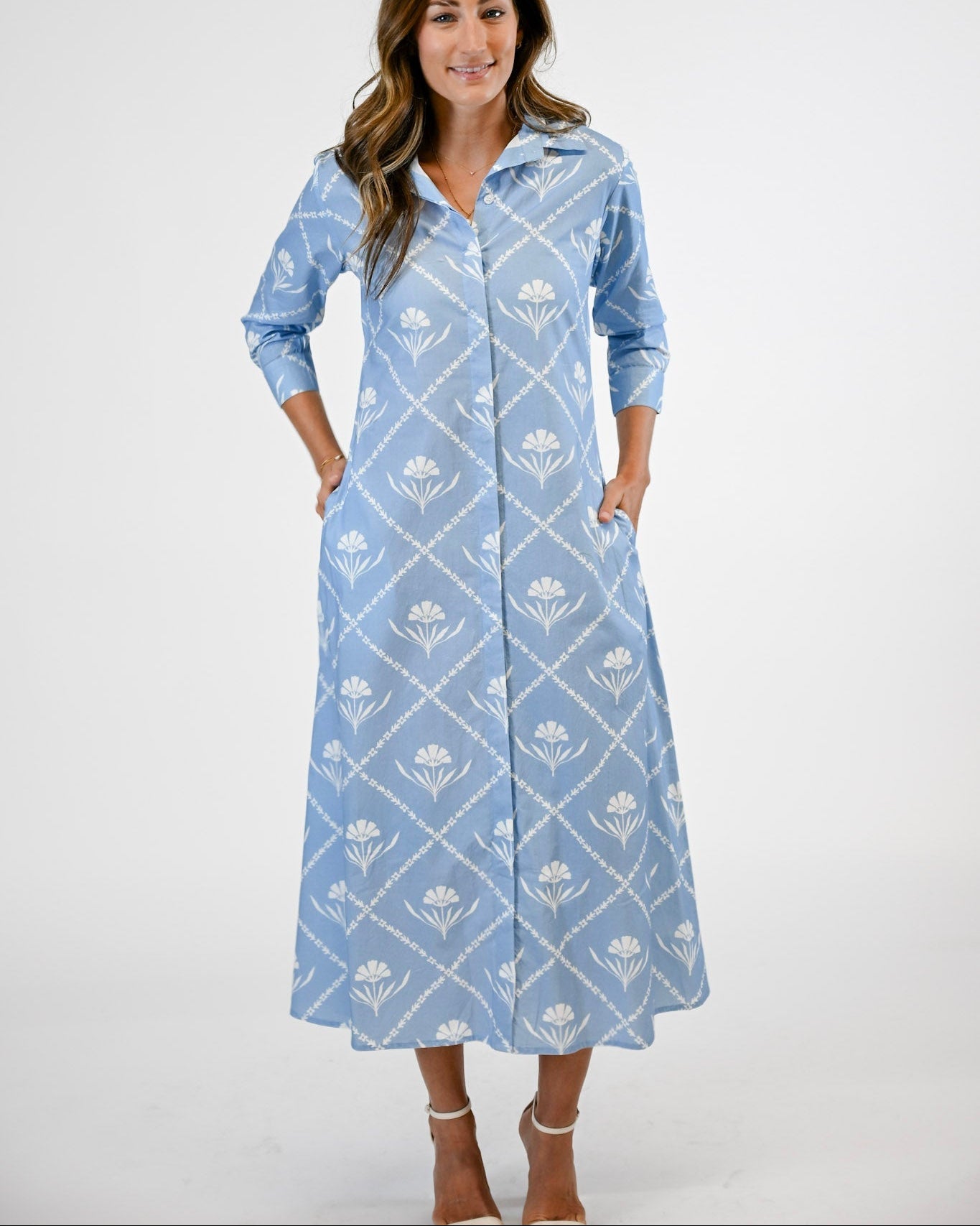 Woman wearing a long blue dress with white floral pattern on a white background