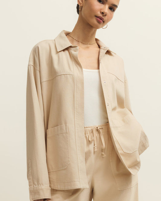 Woman wearing a beige jacket and pants on a plain background