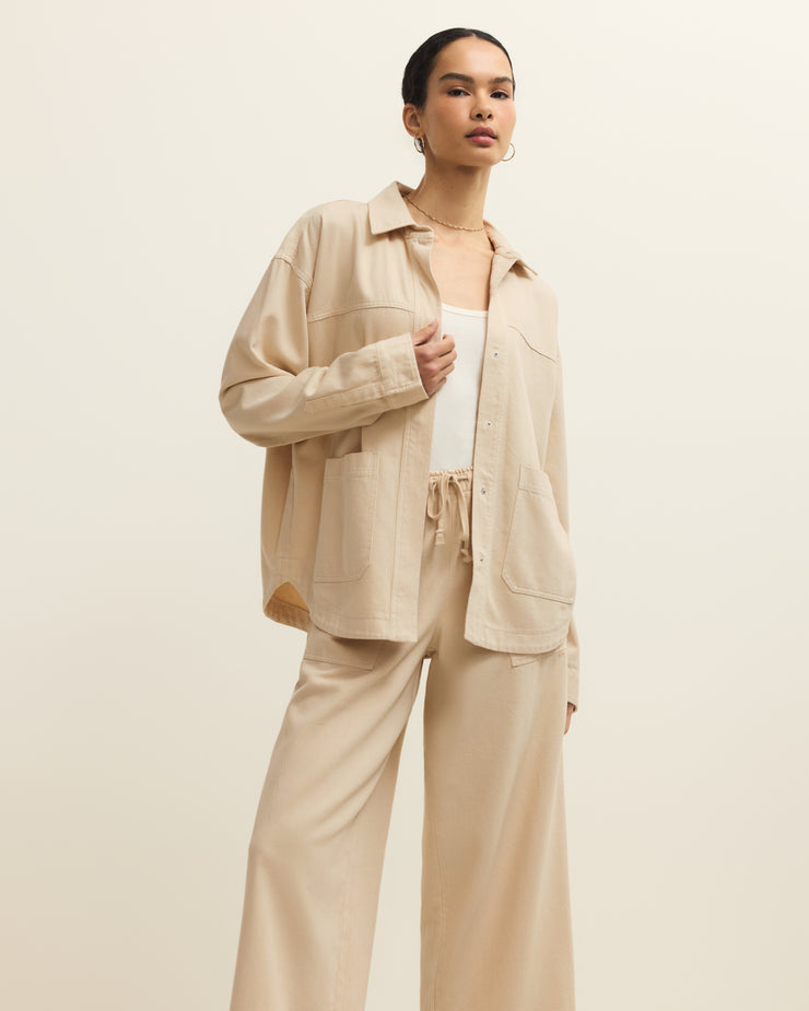 Woman wearing a beige outfit with a jacket and pants on a plain background