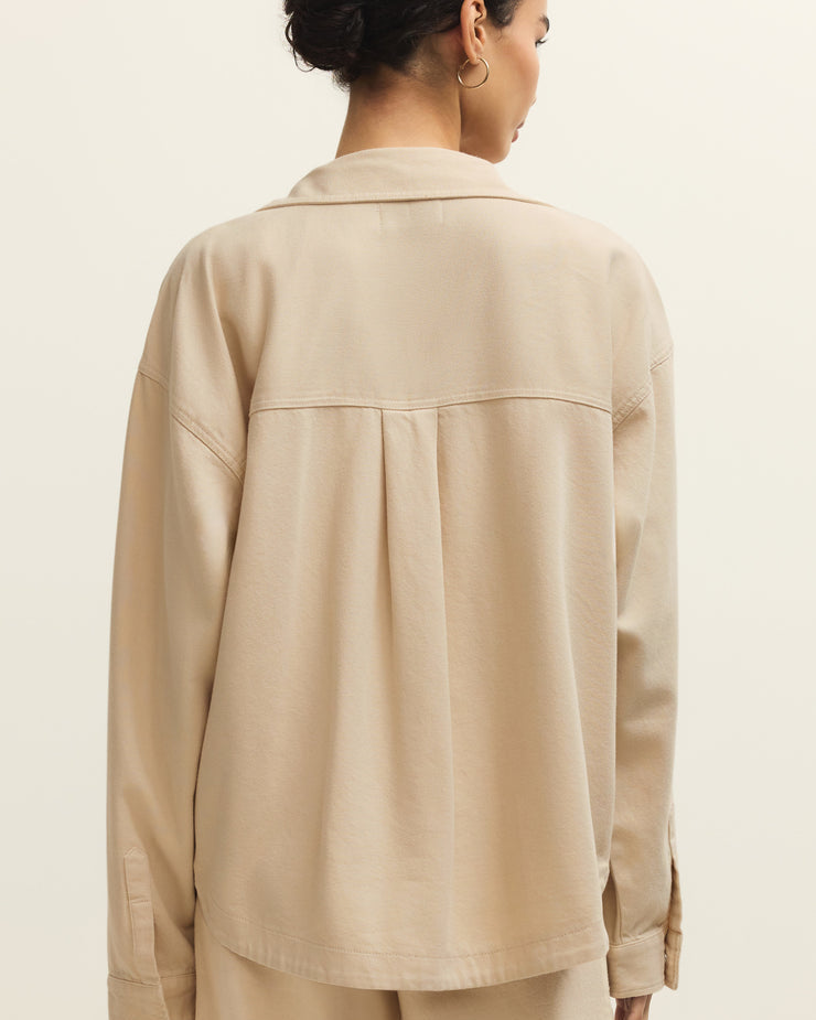 Person wearing a beige jacket and pants on a plain background